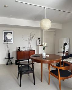 a dining room table with two chairs and a vase on the table in front of it