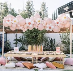 a table with balloons and candles on it in the middle of an outdoor party setting