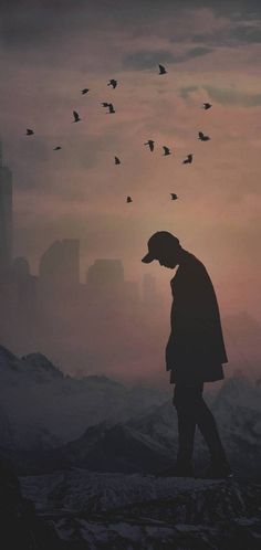 a man standing on top of a snow covered slope next to birds flying in the sky