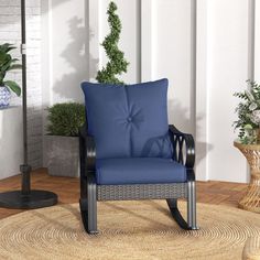 a blue chair sitting on top of a rug next to a potted plant in a living room