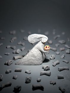 a white rabbit figurine sitting on top of a pile of bone bones with an apple in it's mouth