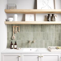 a kitchen with white cabinets and green tile backsplashing, wooden shelves above the sink