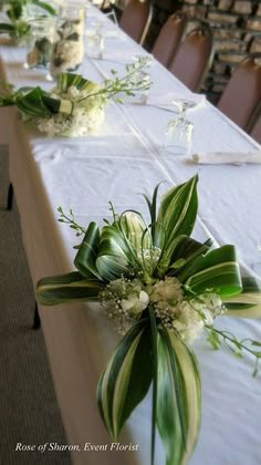 the table is set with white flowers and greenery