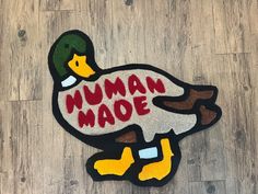 a duck with the words human made on it's back and feet, sitting on a wood floor