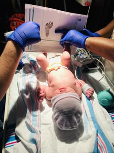 a baby laying on top of a hospital bed being held up by two blue gloves