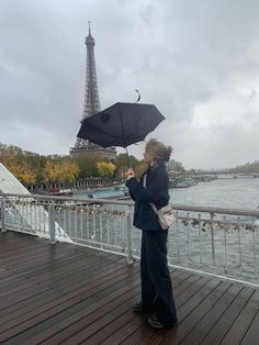 a woman holding an umbrella on top of a wooden deck next to the eiffel tower