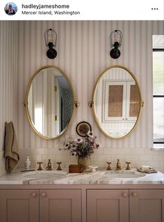 there are two mirrors on the wall above the sinks in this bathroom, one is gold and the other is white