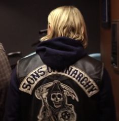 a woman wearing a leather jacket with a skull on it and the words sons anarchy