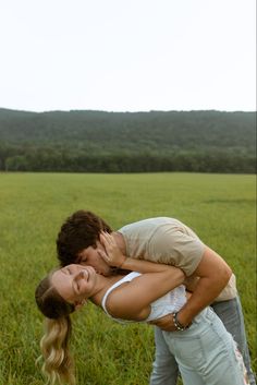 two people are kissing in the middle of a field