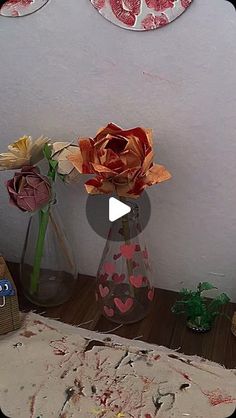 two vases filled with flowers sitting on top of a wooden table next to a wall