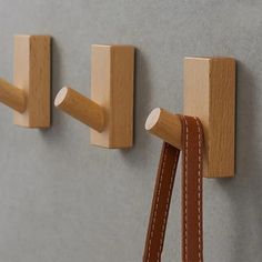 two wooden pegs are attached to the wall and one has a leather strap hanging from it