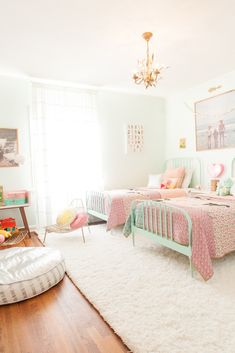 two beds in a bedroom with pink and green decor