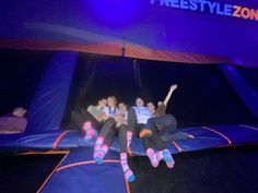 three people are sitting on a trampoline in the air with their arms up