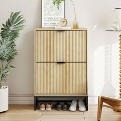 a wooden cabinet sitting next to a lamp and potted plant on top of a hard wood floor