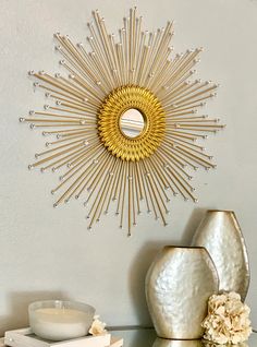 a gold sunburst on the wall above a table with flowers and vases