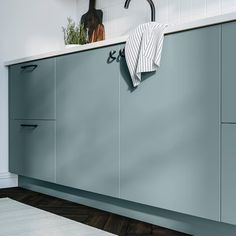 a kitchen with blue cabinetry and white counter tops is shown in this image, there are two black faucets on the wall next to the cabinets