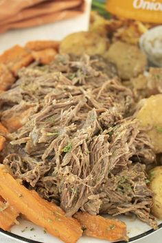 a plate full of food with meat, potatoes and carrots on the side next to a box of crackers