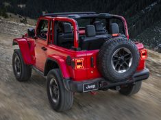 a red jeep driving down a dirt road