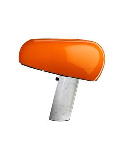 an orange table lamp is shown against a white background with the light reflecting off of it's base