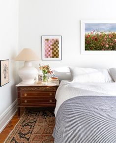 a bedroom with white walls and pictures on the wall