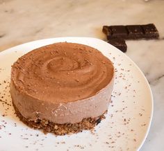 a piece of chocolate cake on a white plate next to some pieces of chocolate bar