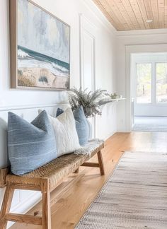 a wooden bench sitting in the middle of a living room next to a painting on the wall