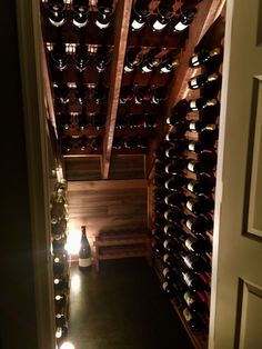 the wine cellar is filled with many bottles and lights on each side of the door