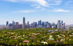 an aerial view of a city with lots of tall buildings and trees in the foreground