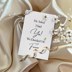 a card that says he asked i said yes we decided on forever with white flowers