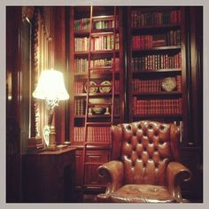 an old leather chair sitting in front of a bookshelf