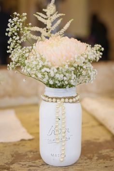 a white mason jar filled with flowers and pearls