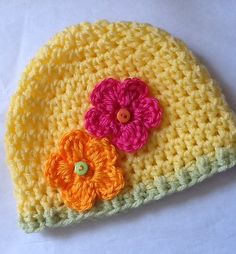 a crocheted hat with two flowers on the front and one flower on the back