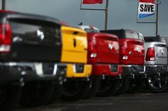 a row of trucks parked next to each other in a parking lot with flags on poles