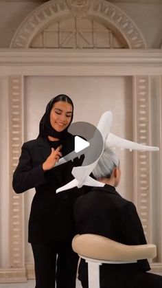 a woman cutting another person's hair in front of a wall with an airplane on it