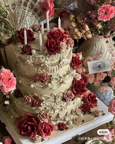 a three tiered cake decorated with flowers and candles