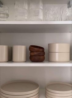 white dishes are stacked on top of each other in the kitchen cupboards and shelves