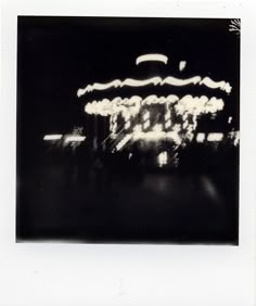 black and white photograph of an amusement park ride at night with blurry lights in the background