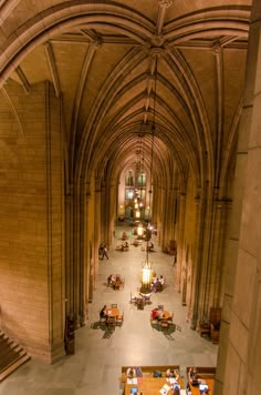 the interior of a large cathedral with tables and people sitting at them on benches in front of an arched ceiling