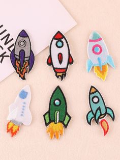 six embroidered patches with different designs on them, including a rocket ship and a space shuttle