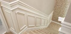 a stair case next to a brick wall and carpeted floor with white trim on it