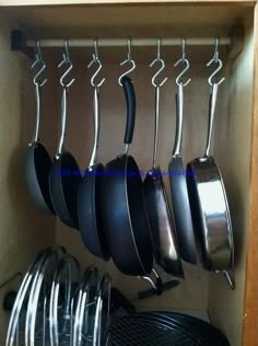 pots and pans hanging from hooks in a cabinet