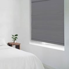 a bed with white sheets and pillows next to a window in a room that has no curtains