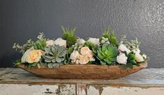 a wooden bowl filled with flowers and succulents