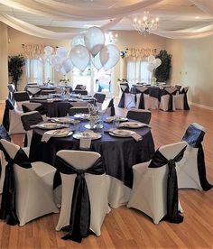 a room filled with lots of tables covered in black and white cloths