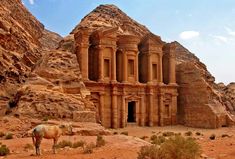 a horse standing in front of an old building surrounded by rocks and desert terrains