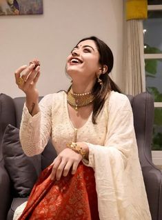 a woman sitting on top of a couch holding a piece of food in her hand