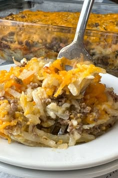 Fork in a plate of cheesy ground beef hash brown casserole Shredded Potatoes And Ground Beef, Cheeseburger Casserole Hashbrown, Hashbrown And Beef Casserole, Hamburger Recipes With Hashbrowns, Hashbrowns And Hamburger, Simple Ground Beef Casseroles, Shredded Hashbrown Casserole Ground Beef, Cheeseburger Casserole Potato, Ground Beef And Shredded Potato Recipes