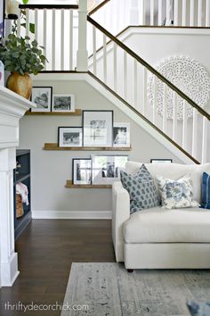 a living room with stairs and pictures on the wall