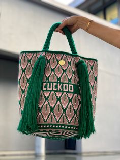 La bolsa de asas de Maria tradicionalmente se llama Mochila por el Wayúu, el grupo indígena colombiano en la costa del Caribe, que los tejeron. 
 Esta bolsa colorida detallada puede demorar hasta 3 semanas para ser realizado por ganchillo con un solo hilo de algodón, por mujeres de Wayuu en La Guajira. 
 El cuerpo en forma de cucharón de bolsa de la bolsa con los patrones tradicionales tejidos que cuentan historias de la vida cotidiana de la tribu. Las manijas trenzadas cortas se terminan c Short Braids, Colorful Bags, Bag Green, Handmade Handbags, The Caribbean, Green Bag, Cotton Thread, Handmade Bags, White Bag