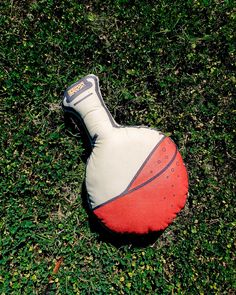 a red and white ball laying on top of green grass